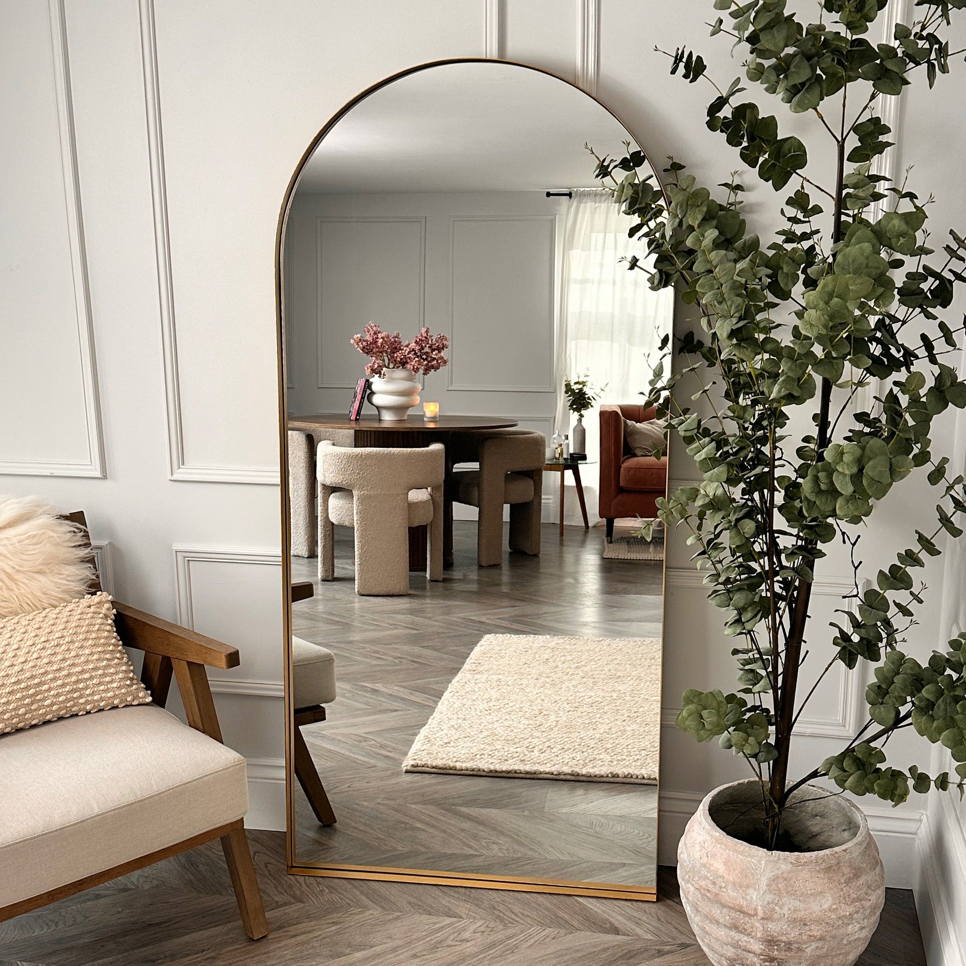 Full length arched Dourado large metal mirror leaning against wall