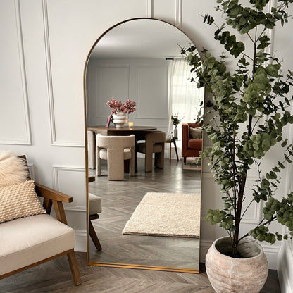Full length arched Dourado large metal mirror leaning against wall