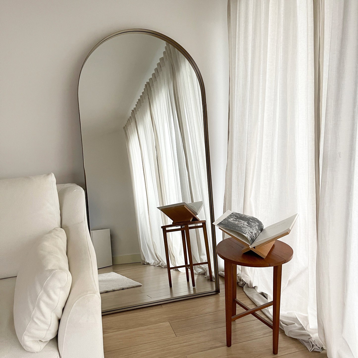 Full length arched Dourado large metal mirror leaning against wall