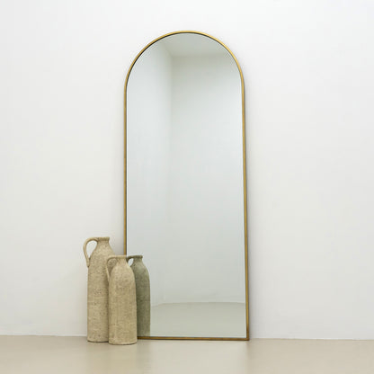 Full Length Dourado Large Arched Metal Mirror beside ceramic vases