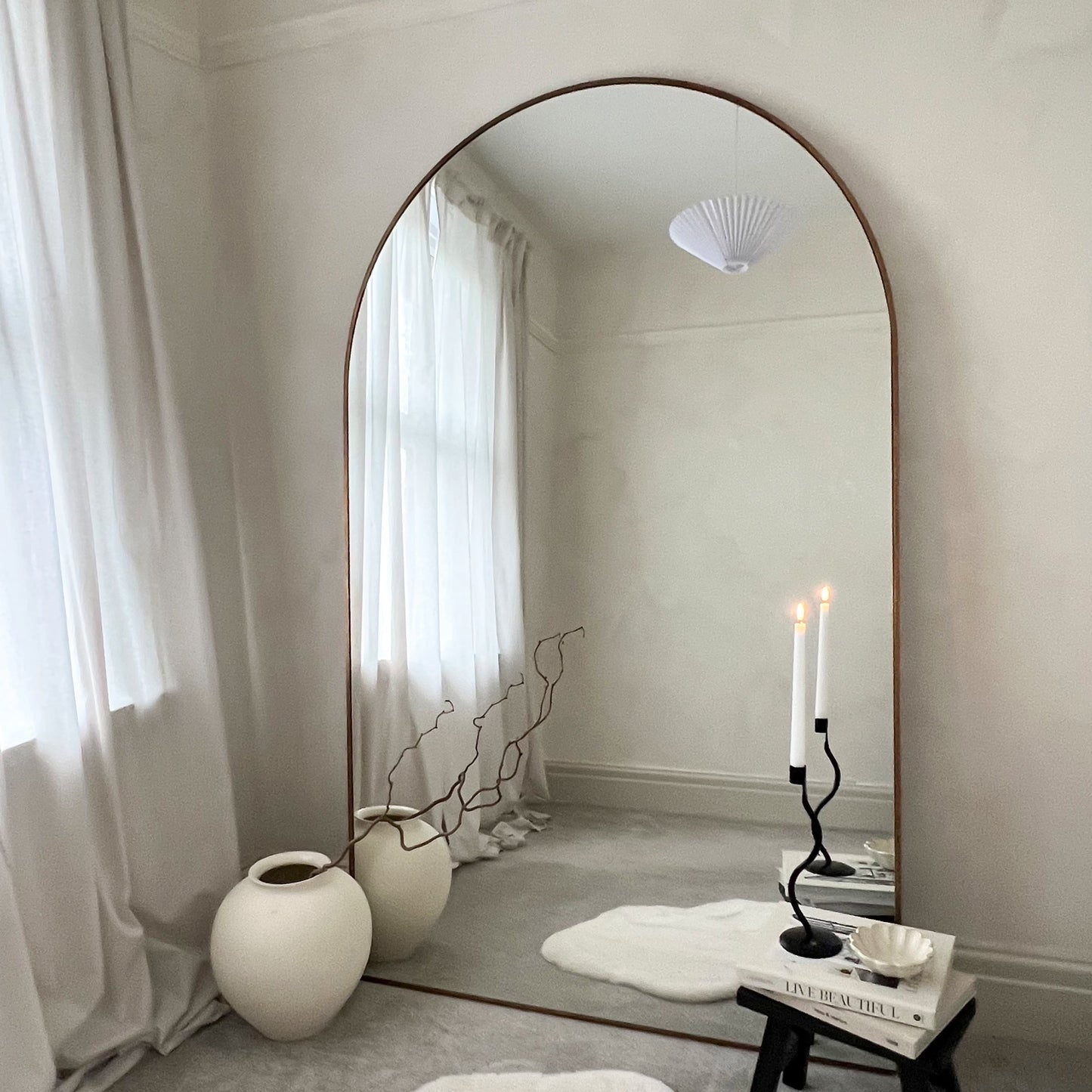 Dourado Full Length Arched Metal Mirror adjacent to vase