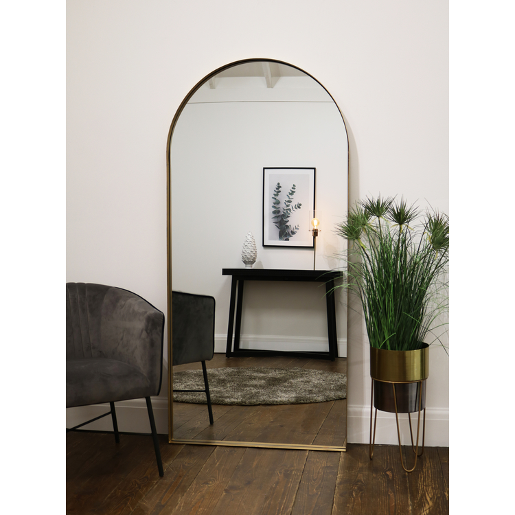 Full length arched Dourado large metal mirror leaning against wall