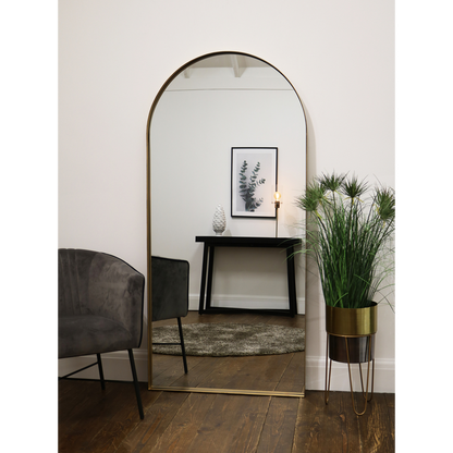 Full length arched Dourado large metal mirror leaning against wall